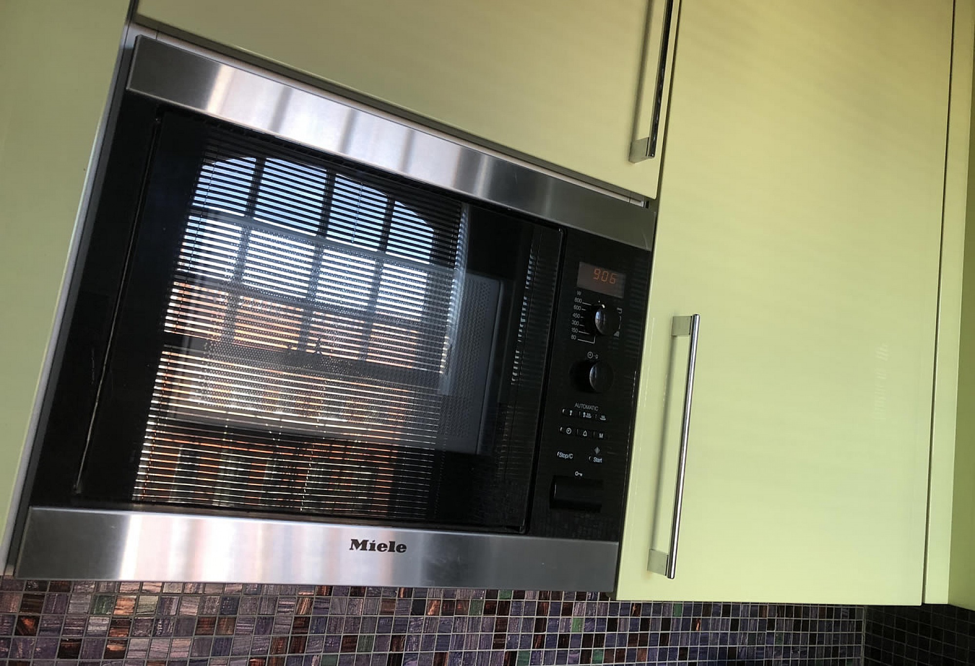 A small bespoke kitchen in Chelsea with Pistachio in high gloss Lacquer integrated Corian sink and Rational furniture, emerald and dark amber Bisazza mosaics