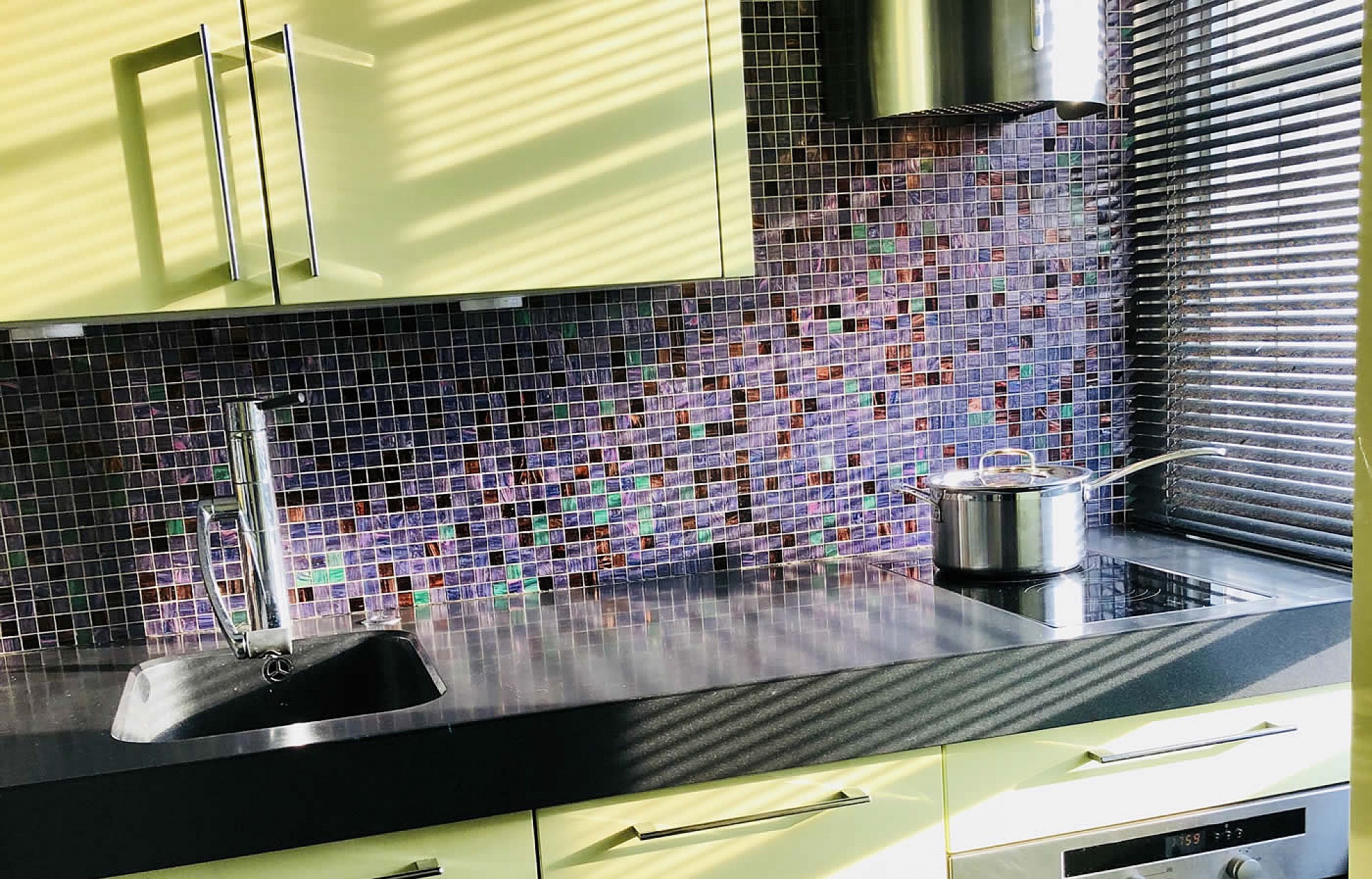 A small bespoke kitchen in Chelsea with Pistachio in high gloss Lacquer integrated Corian sink and Rational furniture, emerald and dark amber Bisazza mosaics
